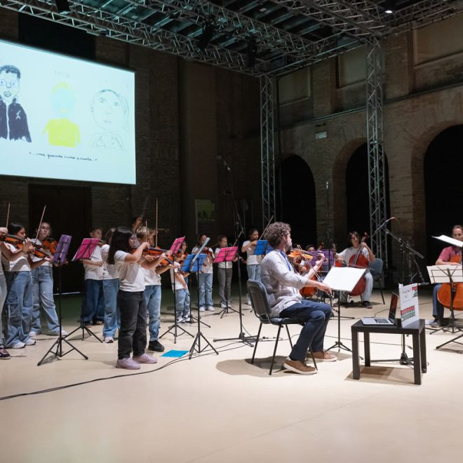 Bambini suonano il violino in concerto mentre sullo schermo scorre un'animazione
