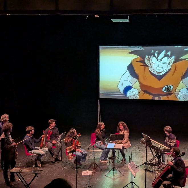 Musicisti suonano sul palco mentre sullo schermo viene proiettato un cartone animato