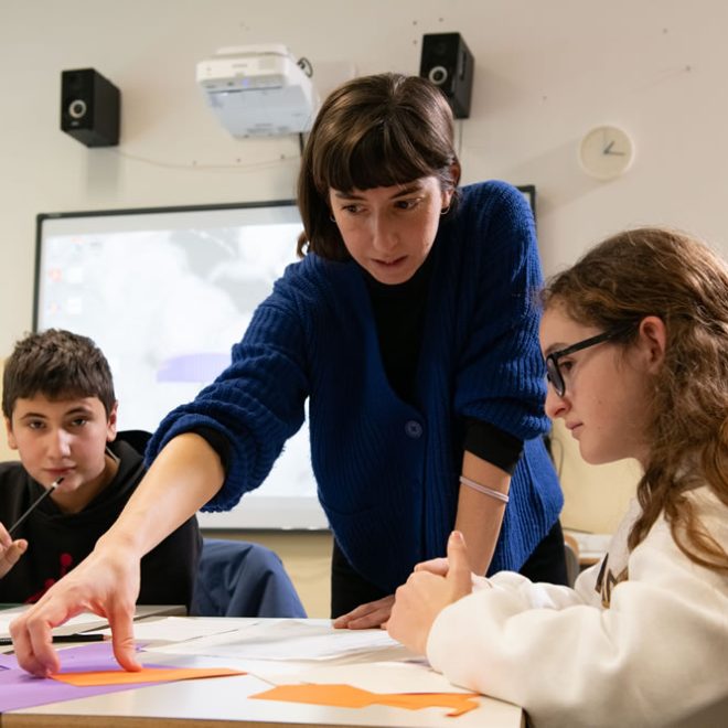 Un'educatrice guida due ragazzi in un'attività di collage al banco