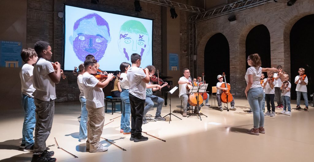 Bambini suonano il violino in piedi in concerto, sullo schermo un'animazione